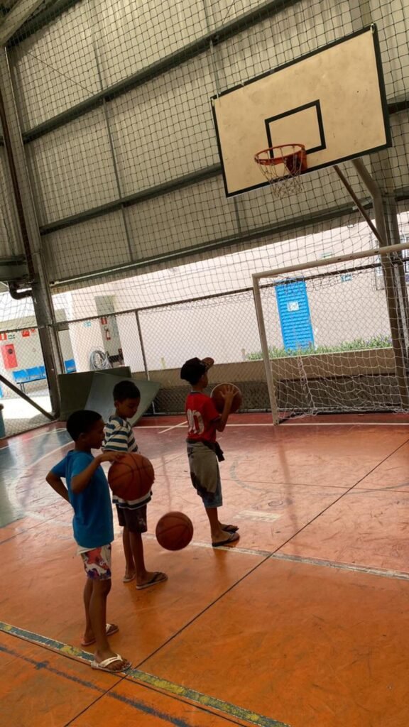 Crianças brincando de basquete no projeto social serra