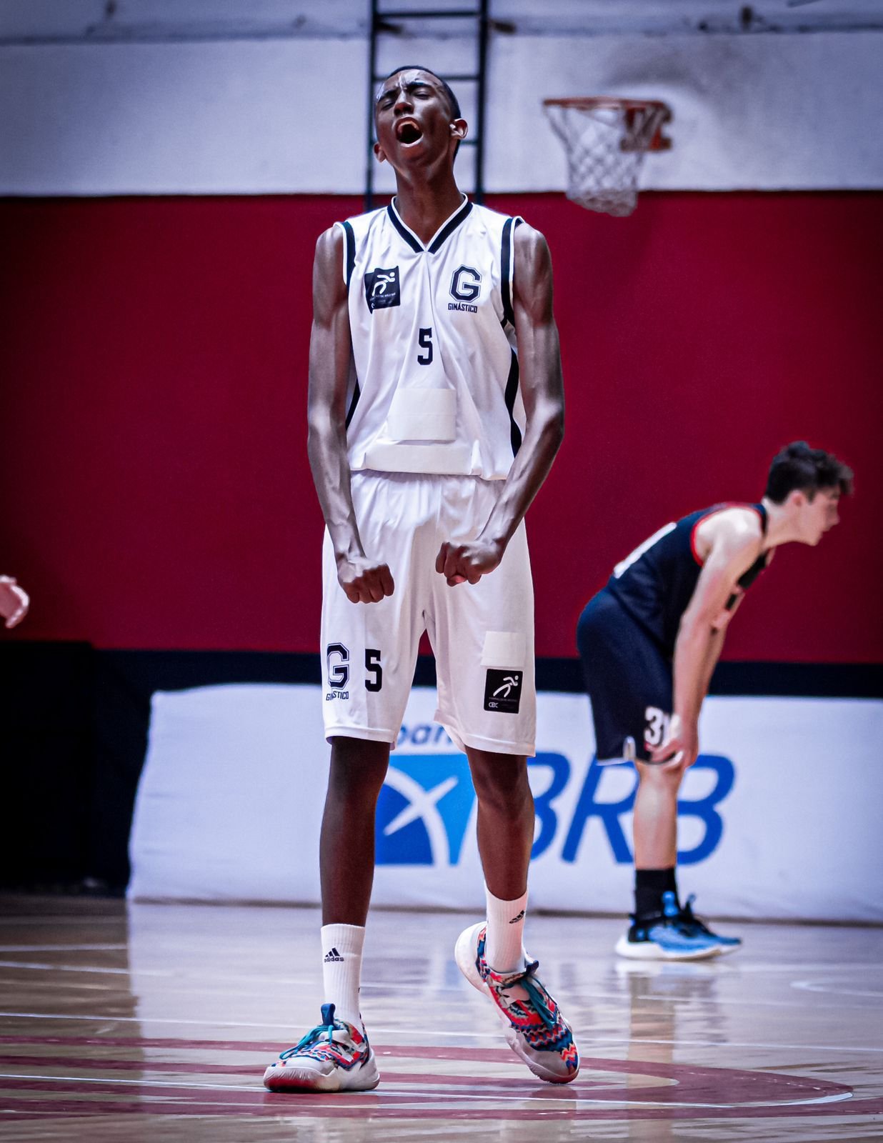 Jovem comemorando sua vitória por ter acertado uma bola na cesta de basquete na quadra da Escola de Basquete