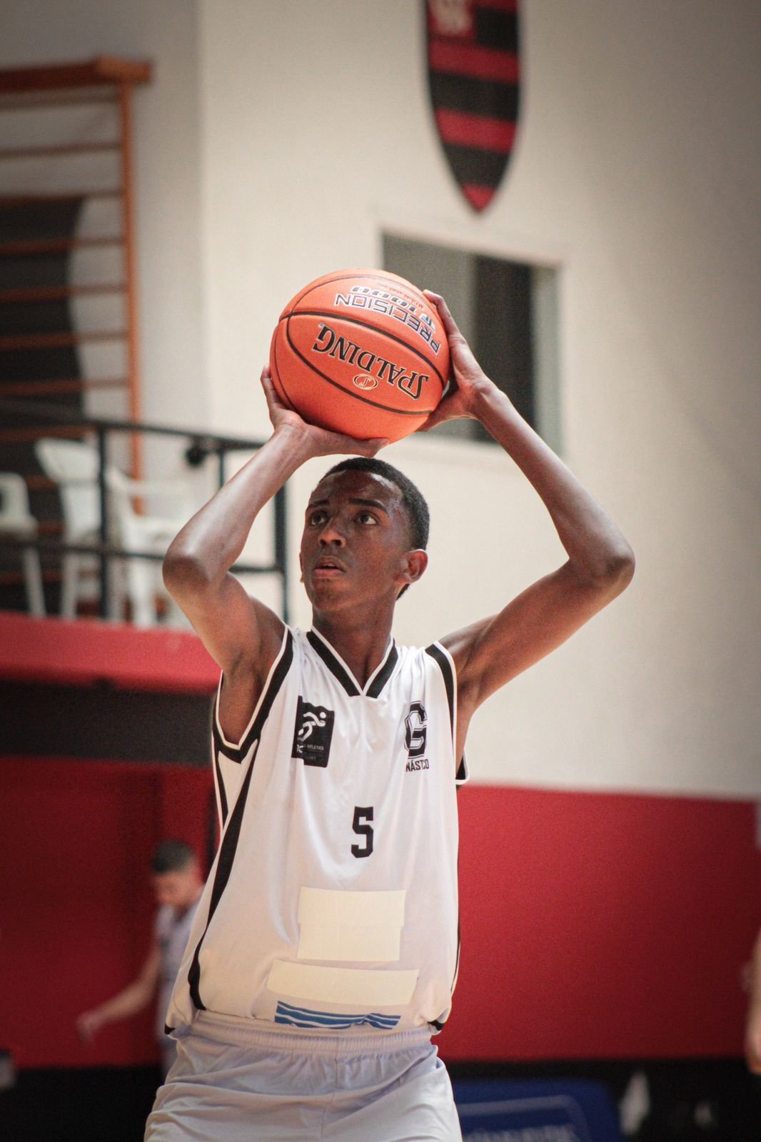 Jovem se preparando para arremessar uma bola na cesta, foto da Escola de Basquete