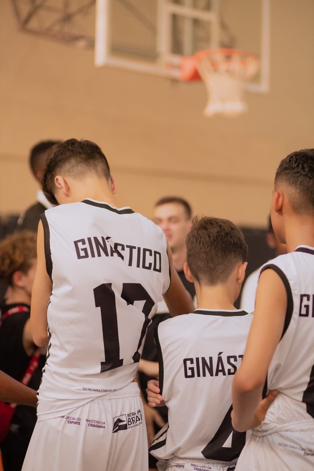 Jovens ouvindo a explicação de um professor na Escola de Basquete