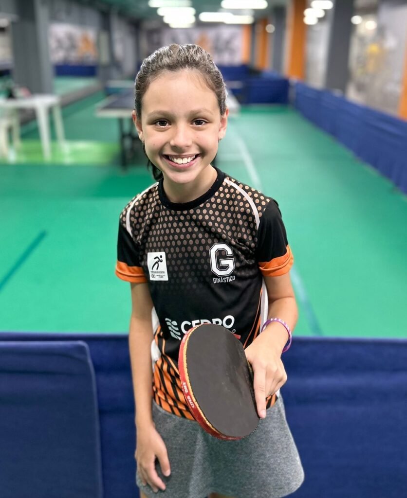 Menina segurando uma raquete, ela é Jogadora de tênis de Mesa do Esporte Clube Ginástico